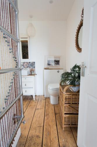 a bathroom with a toilet and a wooden floor at Fairlight - Charming coastal home on the beach in Chichester