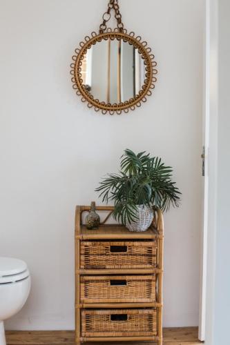 a mirror on top of a wicker cabinet in a bathroom at Fairlight - Charming coastal home on the beach in Chichester
