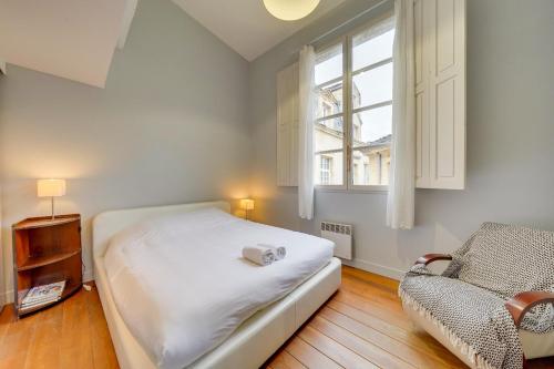 une chambre avec un lit, une chaise et une fenêtre dans l'établissement Observance 2 bedroom duplex apartment, à Bordeaux