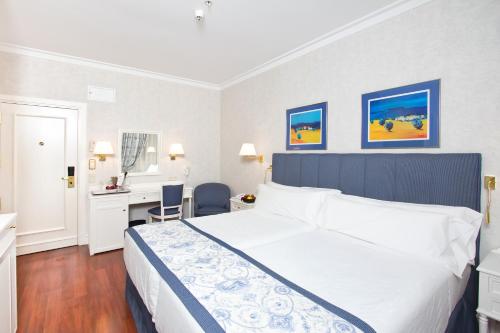 a bedroom with a large white bed and a desk at Hotel Atlántico in Madrid