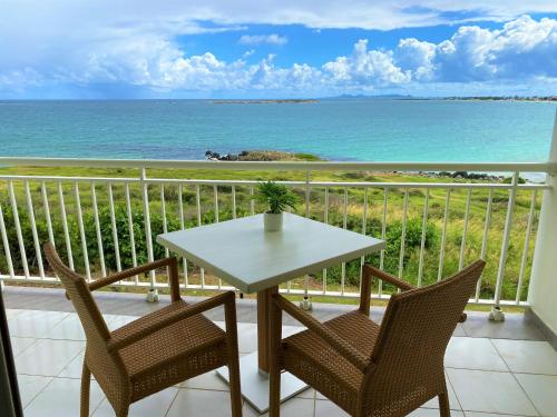 a table and chairs on a balcony with the ocean at Ocean Front studio , step to the beach in Cul de Sac
