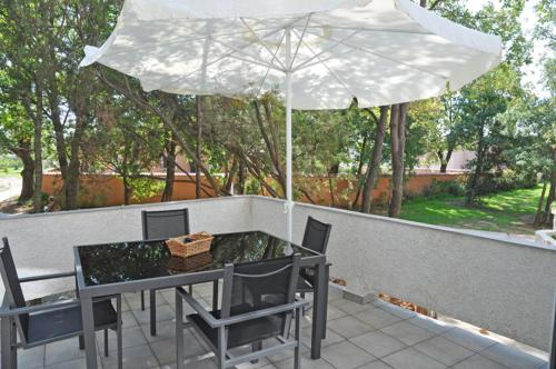 a table and chairs with an umbrella on a patio at Residence de tourisme Le clos des Vendanges in Moriani Plage
