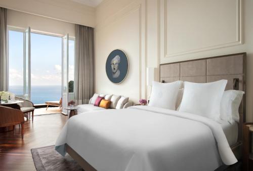 a bedroom with a large white bed and a large window at San Domenico Palace, Taormina, A Four Seasons Hotel in Taormina