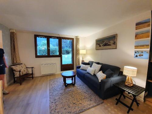 ein Wohnzimmer mit einem Sofa und einem Tisch in der Unterkunft Chamonix Appartement Vue Mont Blanc avec Jardin in Chamonix-Mont-Blanc