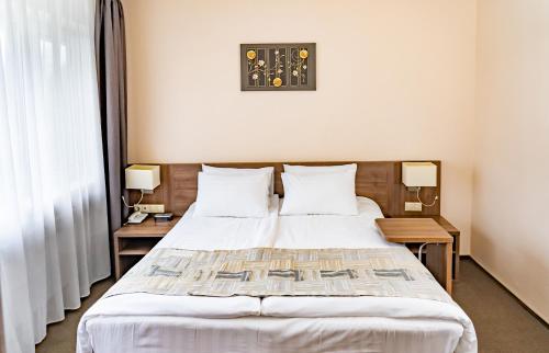 a bedroom with a large bed with two tables and a clock at Health Resort Desna in Voskresenskoye
