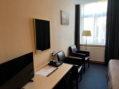 a hotel room with a desk and two chairs at Hotel Nap in West-Terschelling