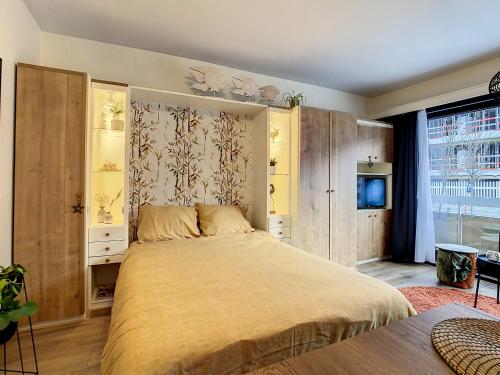 - une chambre avec un grand lit et des placards en bois dans l'établissement Studio enjoy 55, à Nieuport