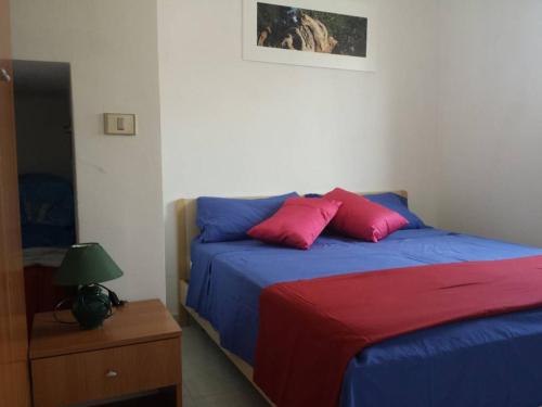 1 dormitorio con 1 cama azul y 2 almohadas rojas en Casa Luigi a 400m Dalla Sabbia en Lido Marini
