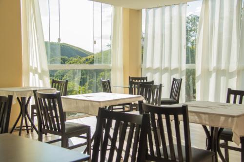 a restaurant with tables and chairs and a large window at Summit Inn Hotel Barra Mansa in Barra Mansa