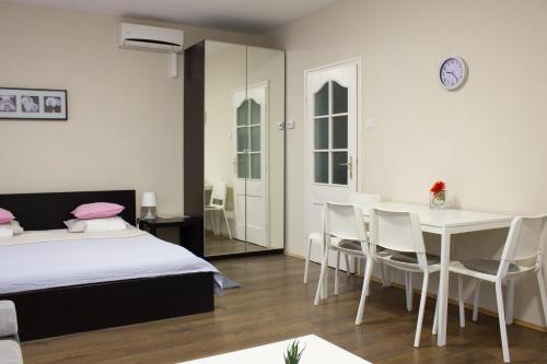 a bedroom with a bed and a table and chairs at Aqua&Luna Apartman in Gyula