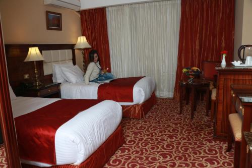 a woman sitting in a hotel room with two beds at The Guard Hotel in Cairo