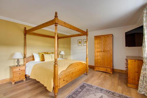 a bedroom with a wooden canopy bed and a tv at Home Farm B&B - Sunflower Room in Forfar