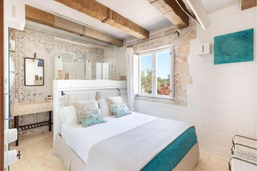 een slaapkamer met een wit bed en een raam bij Trullo Atena in Alberobello