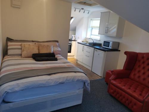 a bedroom with a bed and a red chair at Unique Studio III with free WIFI in Maidstone