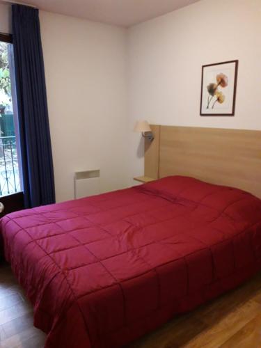 - une chambre avec un lit rouge et une fenêtre dans l'établissement LES JARDINS DE RAMEL, à Luchon