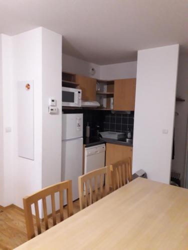 une cuisine avec une table et des chaises et un réfrigérateur blanc dans l'établissement LES JARDINS DE RAMEL, à Luchon