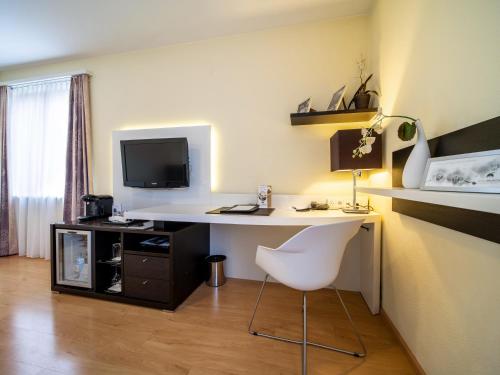 a room with a desk with a chair and a television at Hotel Spalentor - Ihr sympathisches Stadthotel in Basel