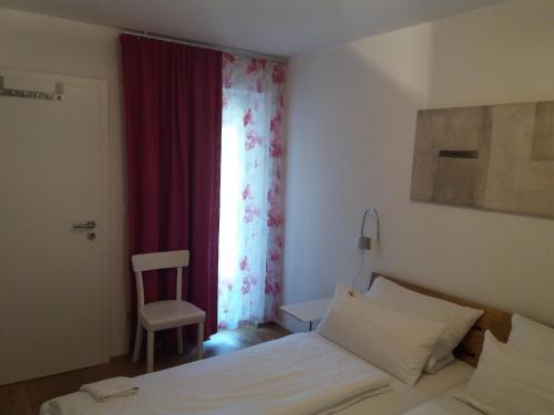 Schlafzimmer mit einem Bett und einem Fenster mit einem Stuhl in der Unterkunft Ferienwohnung Adlmaier in Chieming