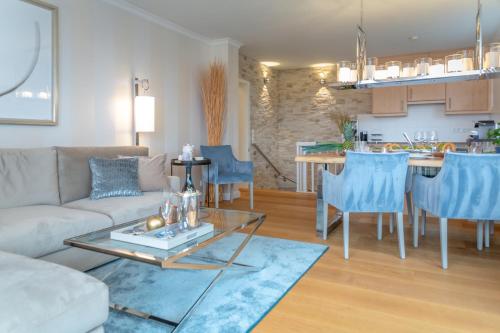 ein Wohnzimmer und eine Küche mit einem Sofa und einem Tisch in der Unterkunft Ferienwohnung Luxus mit Wattenmeerblick in Morsum