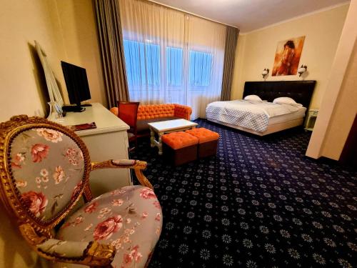 a hotel room with a bed and a chair at Hotel Coandi in Arad