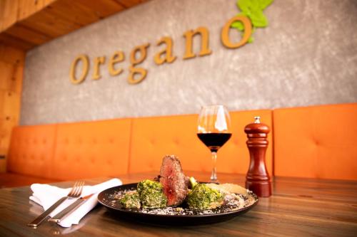 a plate of meat and broccoli and a glass of wine at Hotel Santorini in Guatapé