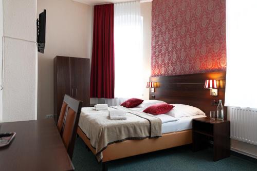 a bedroom with a bed with red walls and a window at Hotel Polonia - Frankfurt/Oder in Frankfurt/Oder