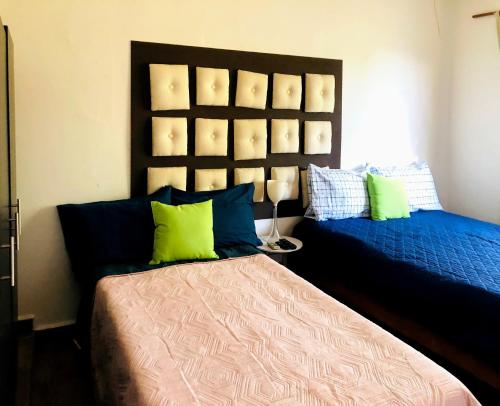 1 dormitorio con 2 camas y almohadas azules y verdes en Casa Angeles, en Nuevo Vallarta 
