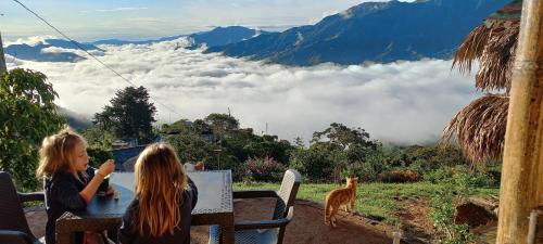two girls sitting at a table with a view of clouds and mountains at Ecohotel Soplo del Tambo in Cocorná