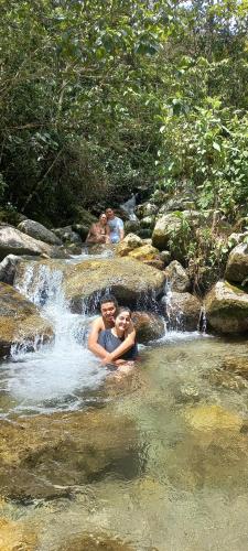 two people are swimming in a waterfall at Ecohotel Soplo del Tambo in Cocorná
