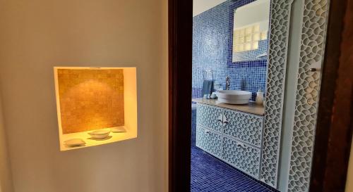 a bathroom with a sink and a blue tiled wall at Villa del Mar in Mazotos
