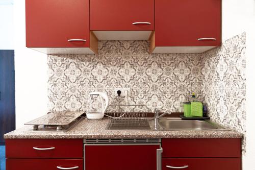 a kitchen with red cabinets and a sink at Hotel Polonia - Frankfurt/Oder in Frankfurt/Oder