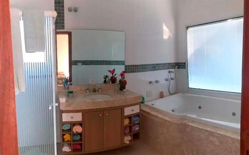 ein Bad mit einem Waschbecken, einer Badewanne und einem Fenster in der Unterkunft Casa em Avaré ao lado da Represa do Jurumirim in Palmeiras