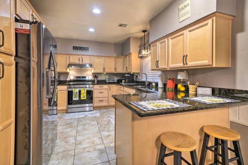a kitchen with wooden cabinets and a counter with stools at Home with Screened Porch about 10 Miles to Dtwn OKC! in Moore