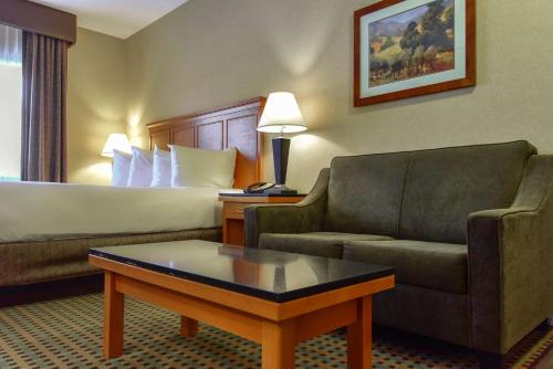 a hotel room with a bed and a couch and a coffee table at Best Western Plus Osoyoos Hotel & Suites in Osoyoos