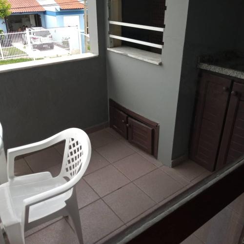 a white chair sitting on a floor next to a window at Pousada Japeju in Capão da Canoa