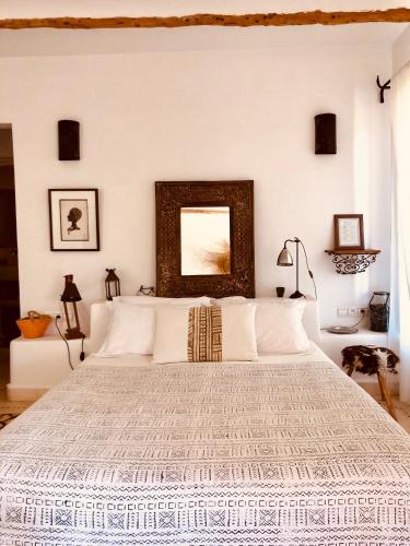 a bedroom with a white bed with a mirror on the wall at Dar Alya Essaouira Maison et table d'hôtes in Ghazoua