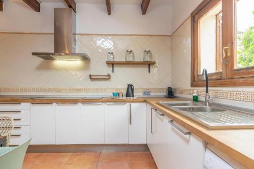 eine Küche mit weißen Schränken und einer Spüle und einem Fenster in der Unterkunft Saran in Llucmajor