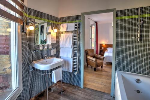 a bathroom with a sink and a tub and a bedroom at Hotel Le Rayon Vert in Étretat