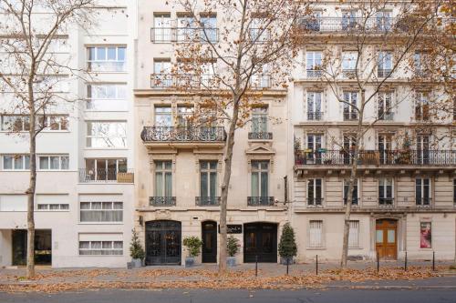 un gran edificio blanco con árboles delante de él en Sonder L'Edmond Parc Monceau, en París