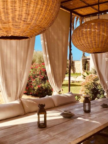 a wooden table with white curtains and lights on it at Dar Alya Essaouira Maison et table d'hôtes in Ghazoua