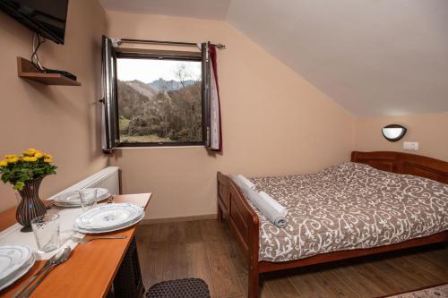 a bedroom with a bed and a table and a window at Vila Nada in Crni Vrh