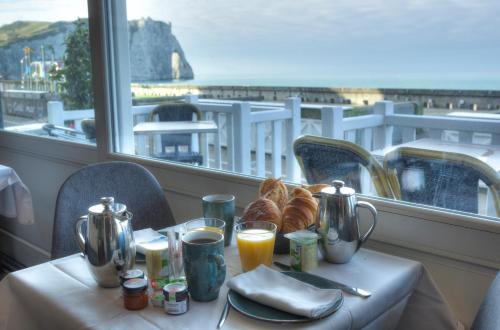 een tafel met brood en jus d'orange en uitzicht op de oceaan bij Hotel Le Rayon Vert in Étretat