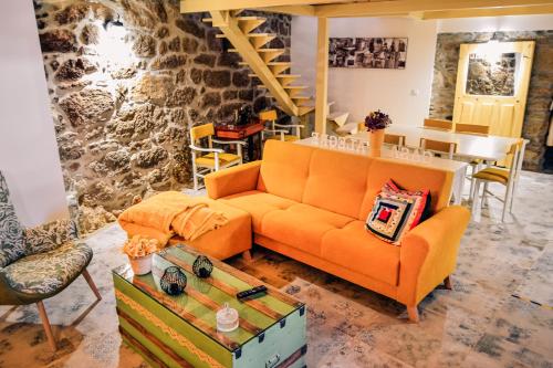 a living room with an orange couch and a table at A Casa Alegre in Miranda do Douro