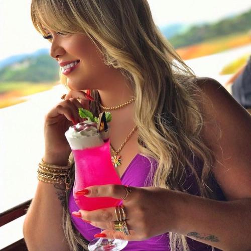 a woman in a purple dress holding a drink at Chalé das Águas in Igaratá