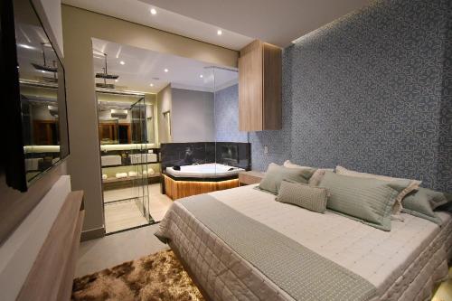 a bedroom with a large bed and a bathroom at Pousada Chão de Folhas SPA Boutique in Águas de Lindóia