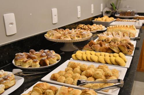 a buffet filled with different types of pastries and pies at Pousada Chão de Folhas SPA Boutique in Águas de Lindóia