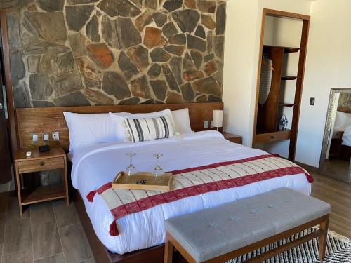 a bedroom with a large bed with a stone wall at Siempre Valle Hotel Boutique in Valle de Guadalupe