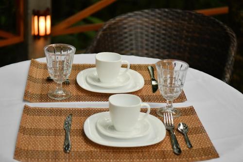 a table with two white cups and plates and silverware at Pousada Chão de Folhas SPA Boutique in Águas de Lindóia