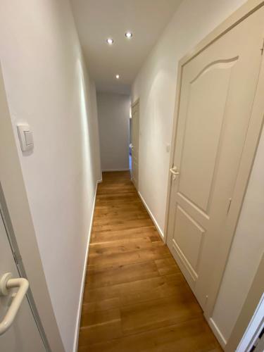 a hallway with a white door and a wooden floor at Ruim appartement gelegen te centrum Knokke in Knokke-Heist