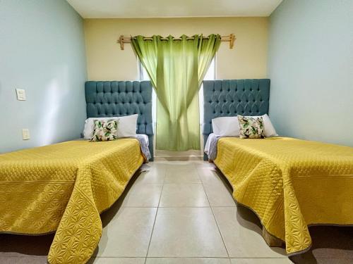 Ocotlán的住宿－Gallery Home，客房设有两张带黄床单的床和窗户。